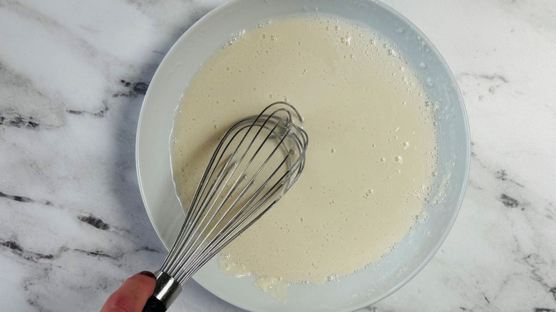 Hand whisking water and flour mixture in bowl