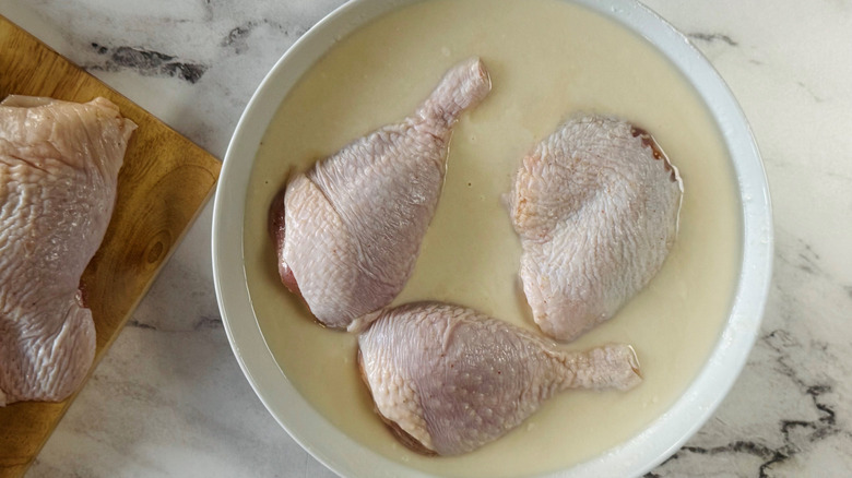Raw chicken pieces sitting in flour and water mixture