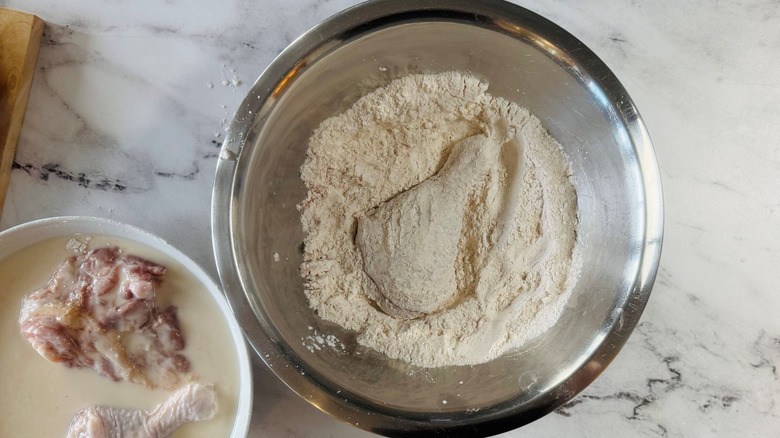 Chicken drumstick sitting in bowl of flour
