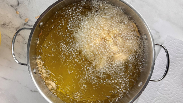 Battered onion frying in pot of oil