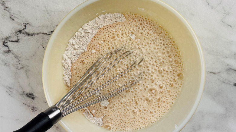 Bubbly flour mixture in bowl with whisk