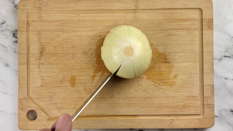 Knife slicing into whole onion