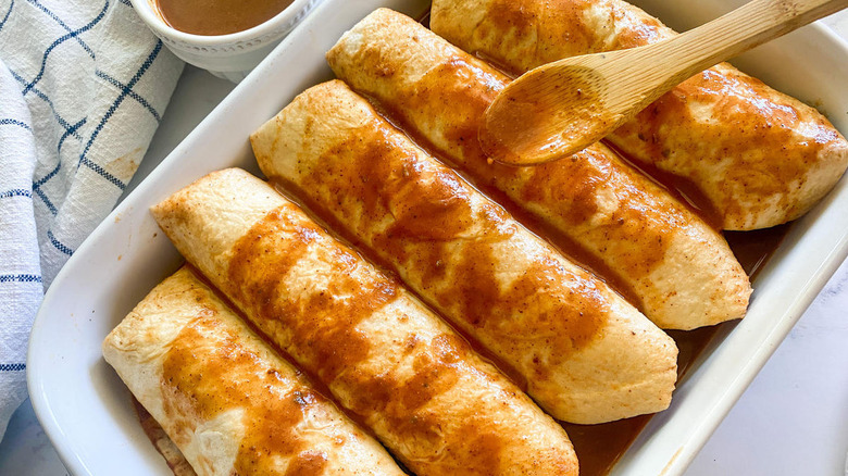drizzling sauce over enchiladas