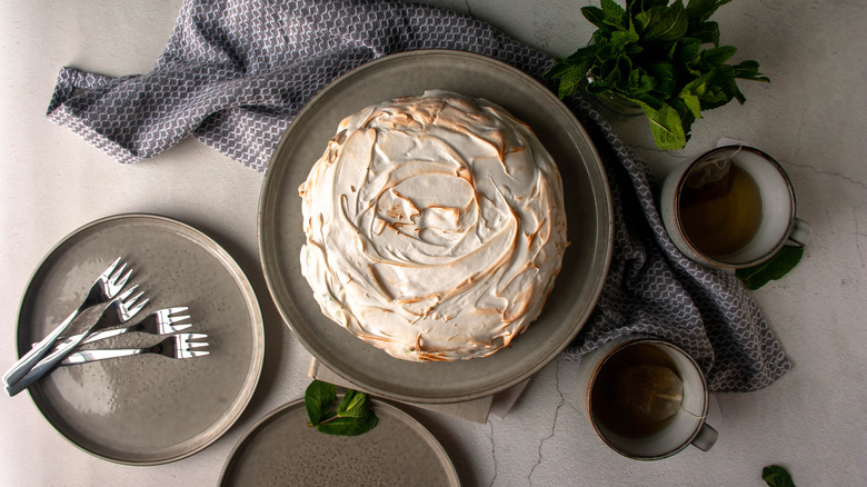 mint baked Alaska on plate from above with mugs of tea and forks