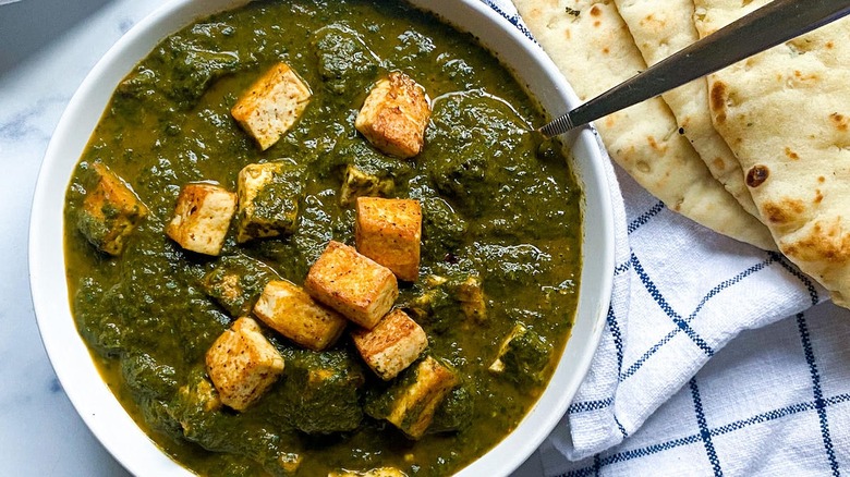 Palak Tofu in bowl with naan bread on side