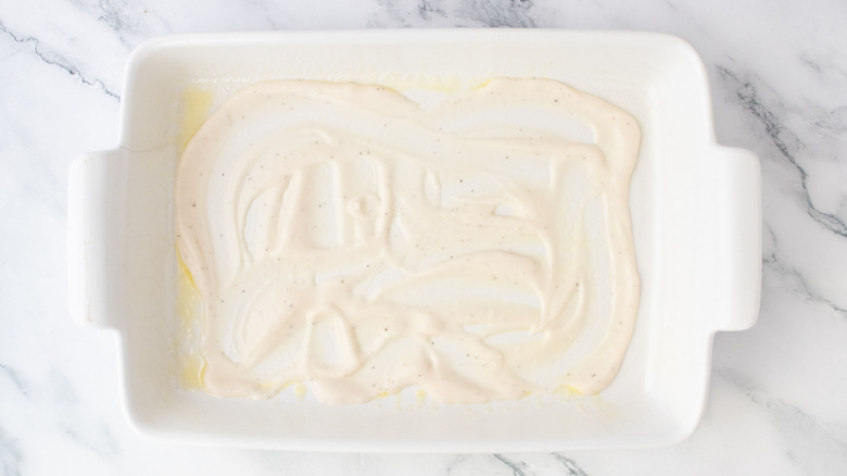 Alfredo sauce spread across bottom of casserole dish