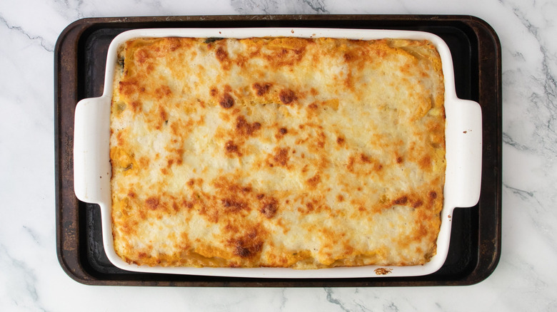 Baked pumpkin lasagna in casserole dish on top of baking sheet