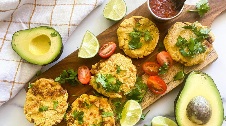 Pupusas garnished on wooden platter with avocado halves and limes