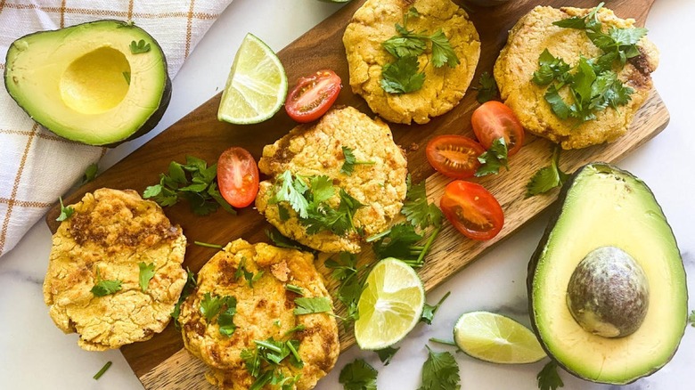 Decorated Pupusas on platter with cherry tomatoes, lime wedges, and avocado halves