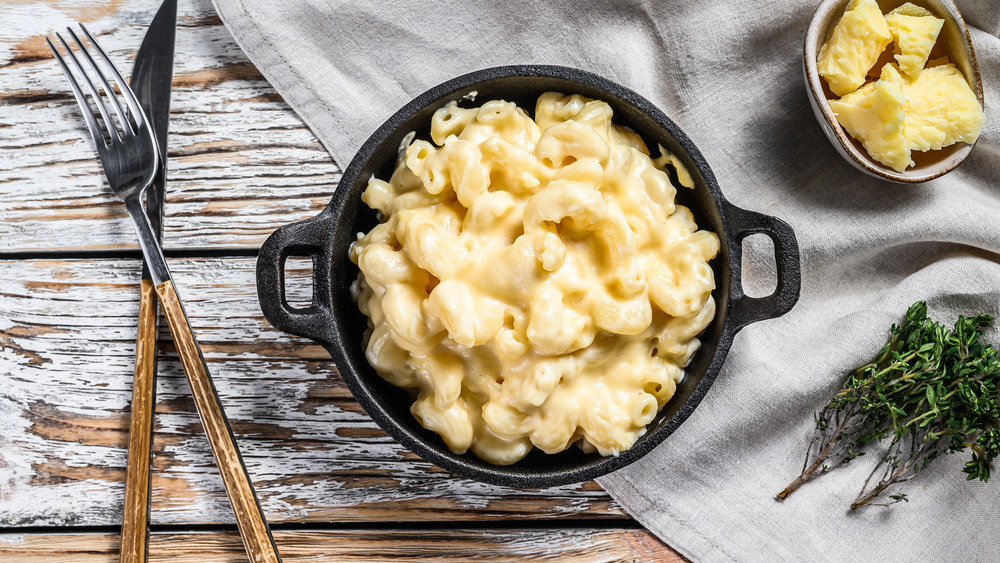 American mac and cheese, macaroni pasta in cheesy sauce. White wooden background. Top view