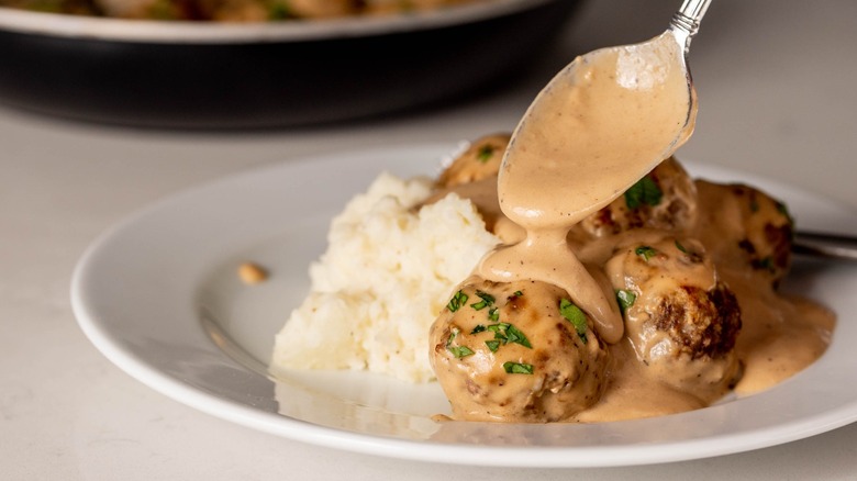 spooning gravy onto swedish meatballs