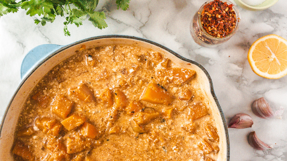 latte di cocco aggiunto alla pentola per la zuppa di zucca