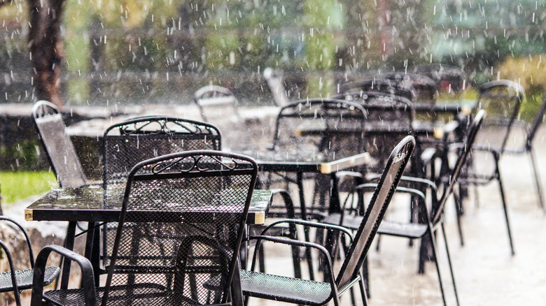 Rain falling on outdoor tables at a restaurant.