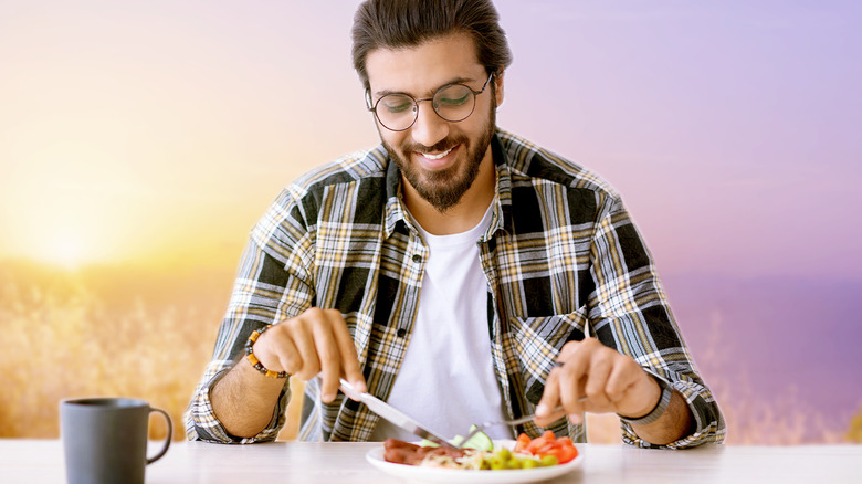 man with glasses eating at sunset