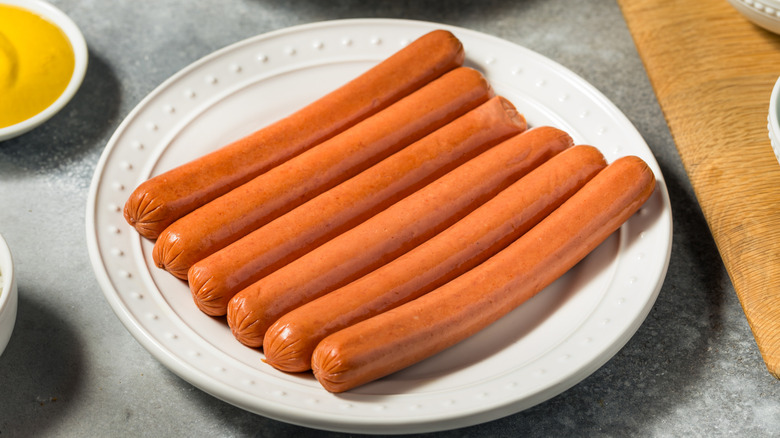 Uncooked hot dogs on plate
