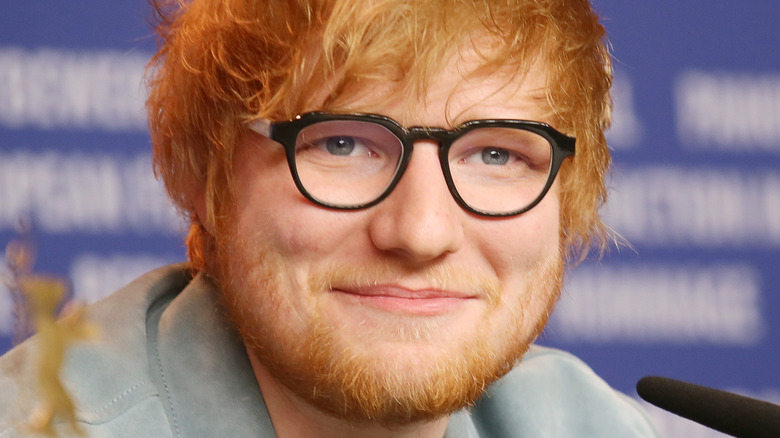 Ed Sheeran wearing black glasses and smiling