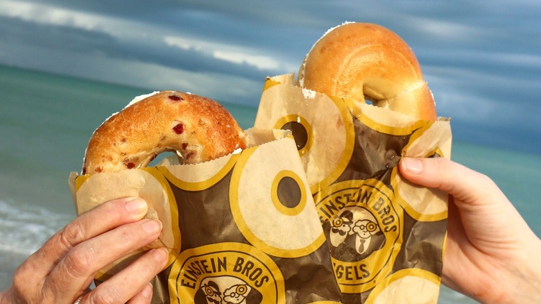 hands holding Einstein Bros. Bagels