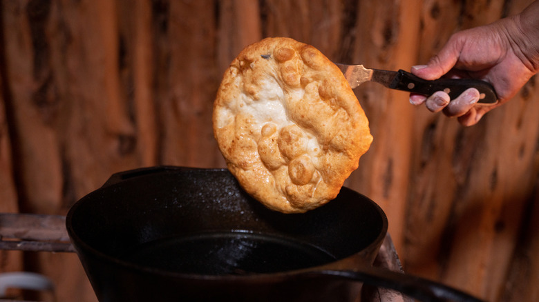 Native American fry bread being taken from a skillet