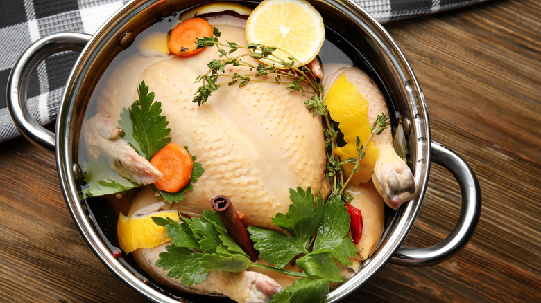 Turkey brining in large pot with lemon, veggies, and herbs