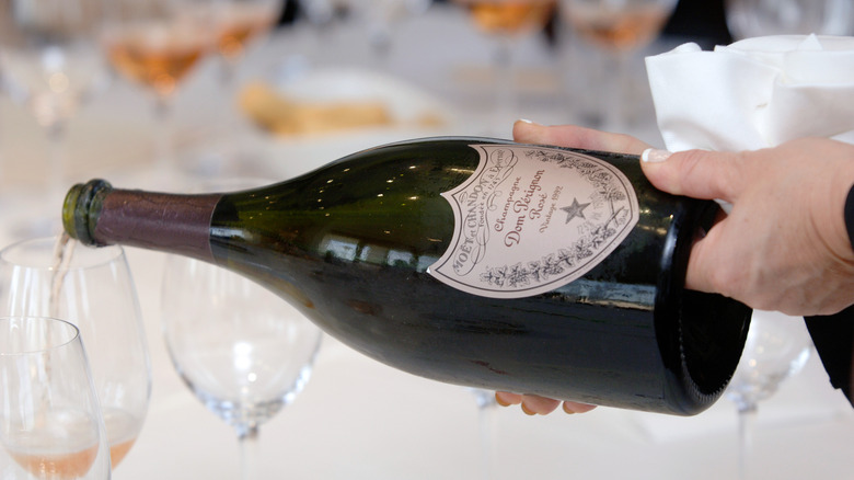 Hands hold and pour a bottle of Dom Pérignon rosé champagne