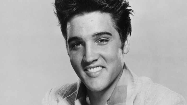 Elvis Presley smiling in a black and white photo