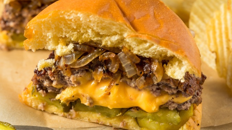 Juicy Lucy burger with pickles and onions on a plate with crinkle-cut chips