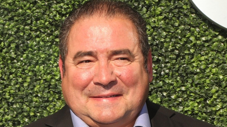 Emeril Lagasse in front of green backdrop