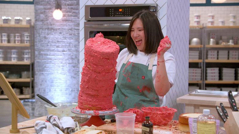 Baker with hands covered in frosting