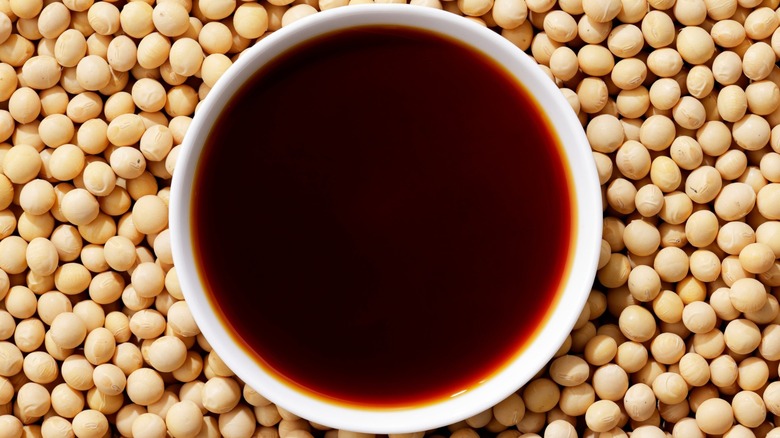 A bowl of soy sauce atop a bed of soybeans
