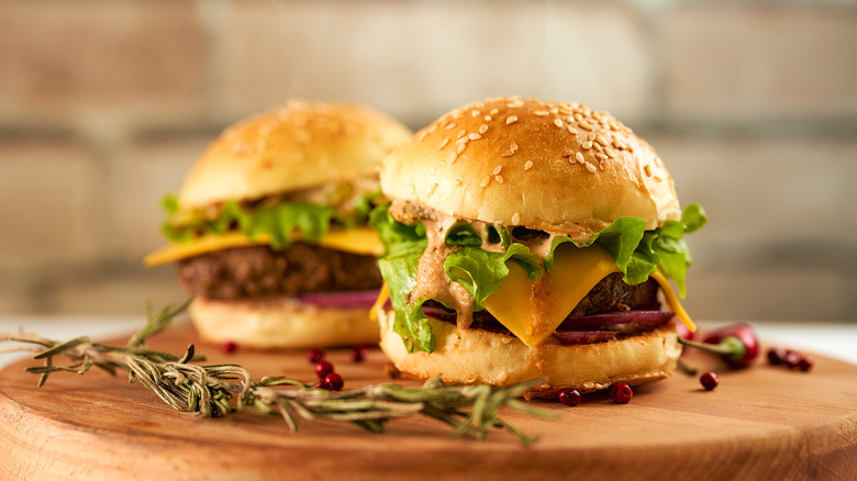 Two burgers on a wooden board