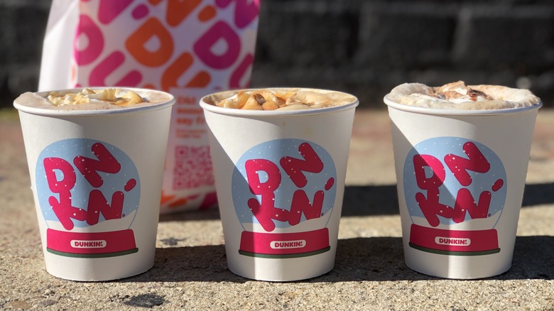 Three cups of dunkin donuts holiday 2021 coffee in front of a dunkin donuts bag