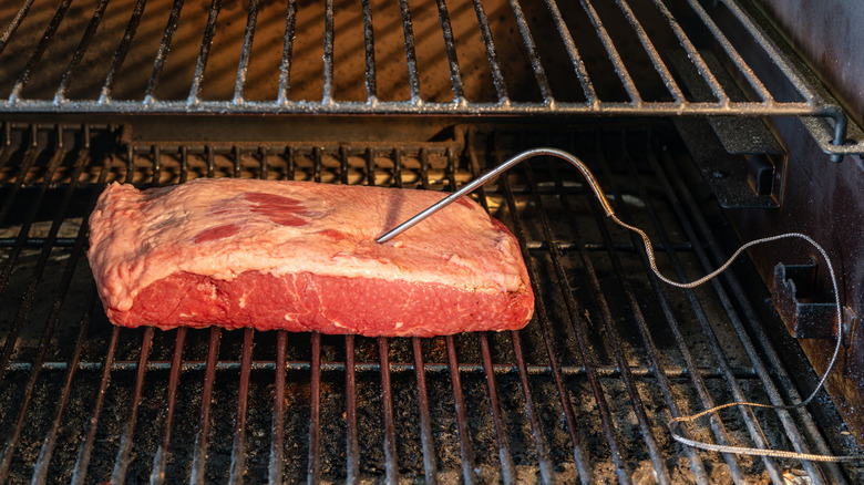Brisket in grill with meat thermometer sticking into it