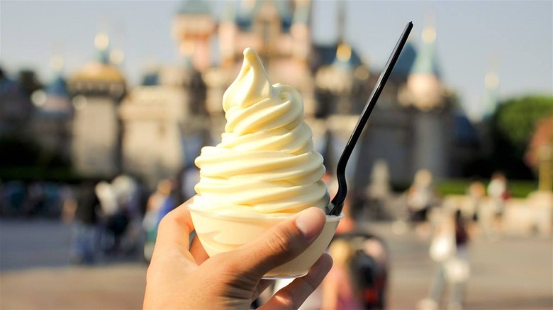 a hand holding a cup of pineapple dole whip at Disneyland