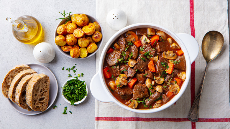 beef bourguignon with potatoes and bread in bowl