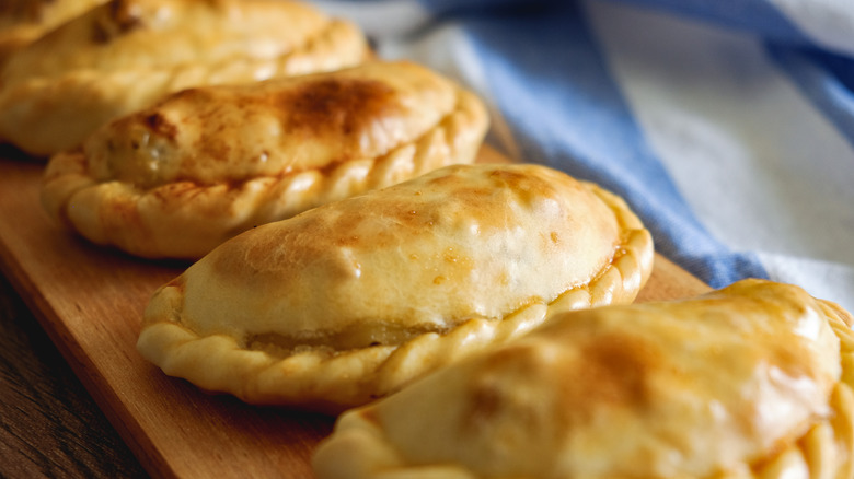 Row of empanadas on a wooden serving dish