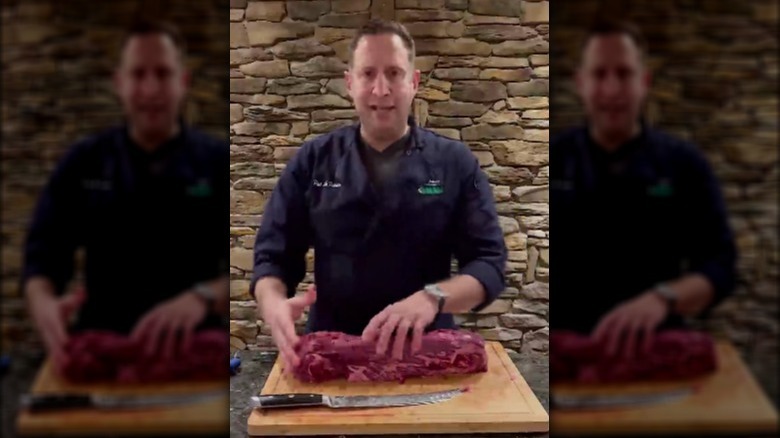 Pat LaFrieda holding raw filet of beef on a cutting board