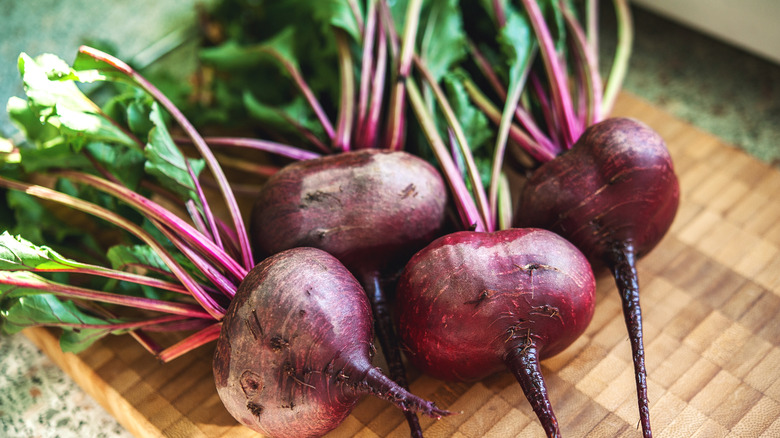 Four whole raw beets on cutting board