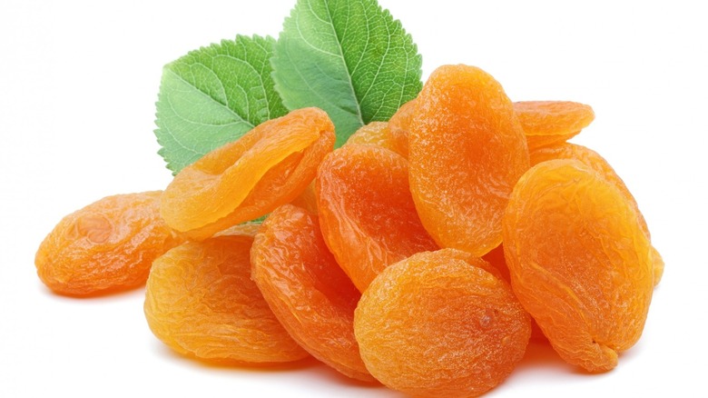 dried apricots with green leaves on white background
