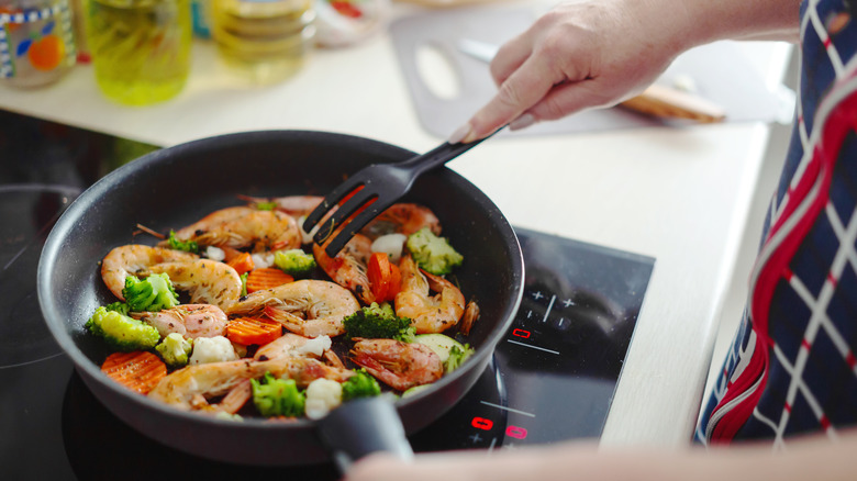 Person preparing shrimp and vegetables