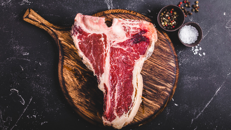 Raw T-bone steak on wooden board