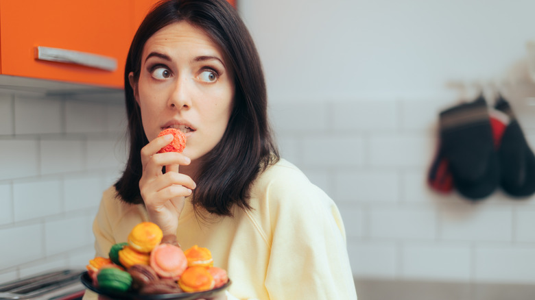 sneaky woman eating macaron cookies