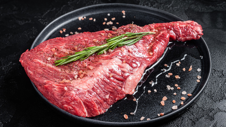 A raw tri-tip steak salted on a plate