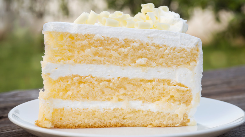 Slice of cake with white icing on white plate