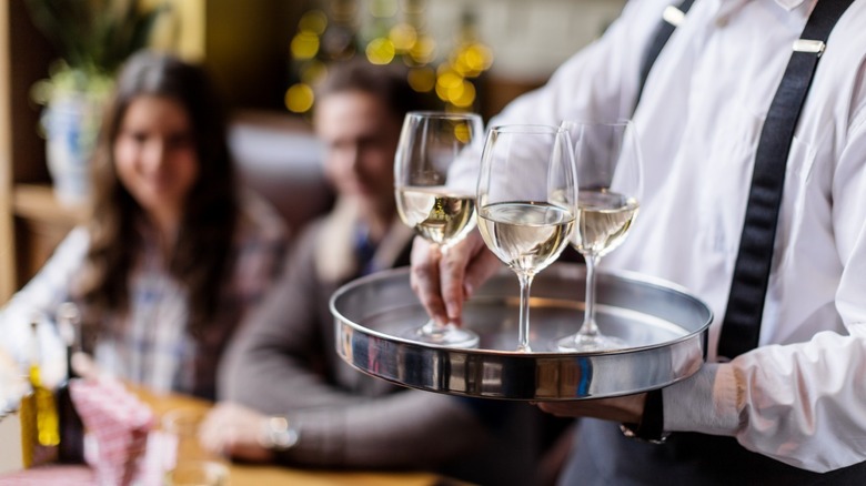 A waiter serving white wine