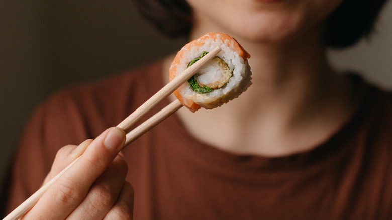 woman picking up sushi roll