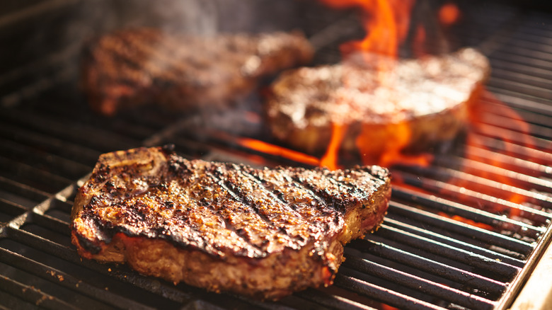 steaks on grill with flames