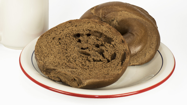 Halved pumpernickel bagel on a white plate