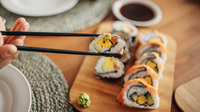 Person eating sushi with chopsticks