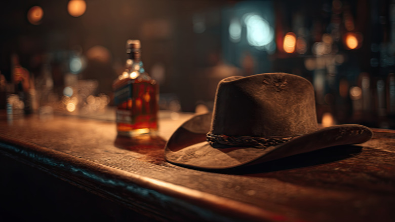Cowboy hat on bar beside bottle of whiskey