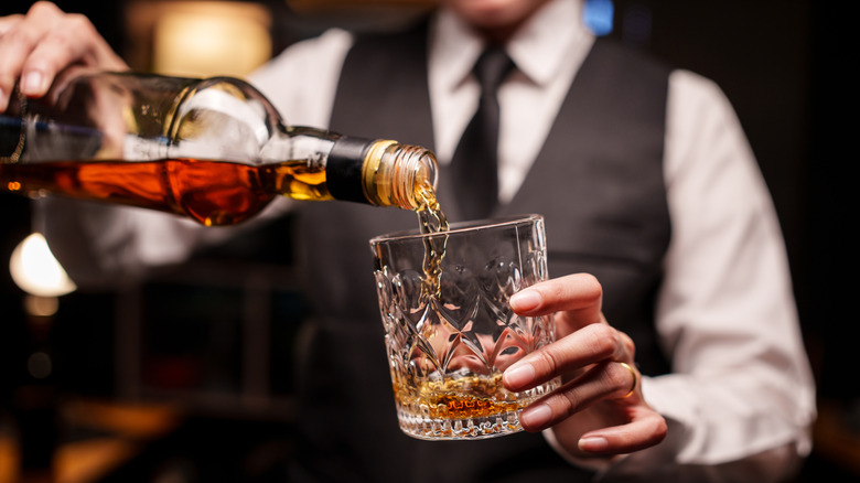 Bartender pouring whiskey into a glass